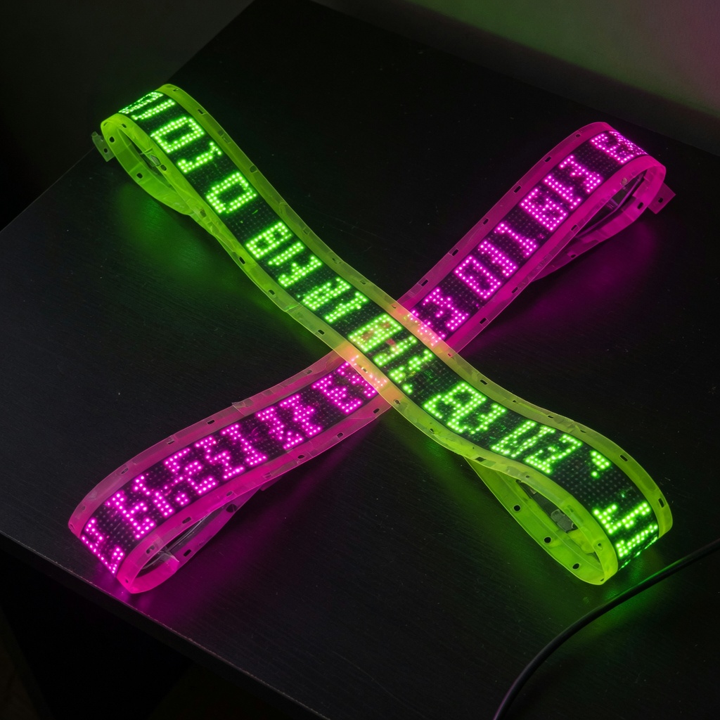 Two neon ticker ribbons crossing on a dark desk